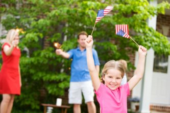 girl waving flags during a backyard 4th of July celebration