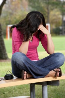 young teenager stressed out sitting along on a park bench