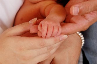 parents holding hand of newborn baby