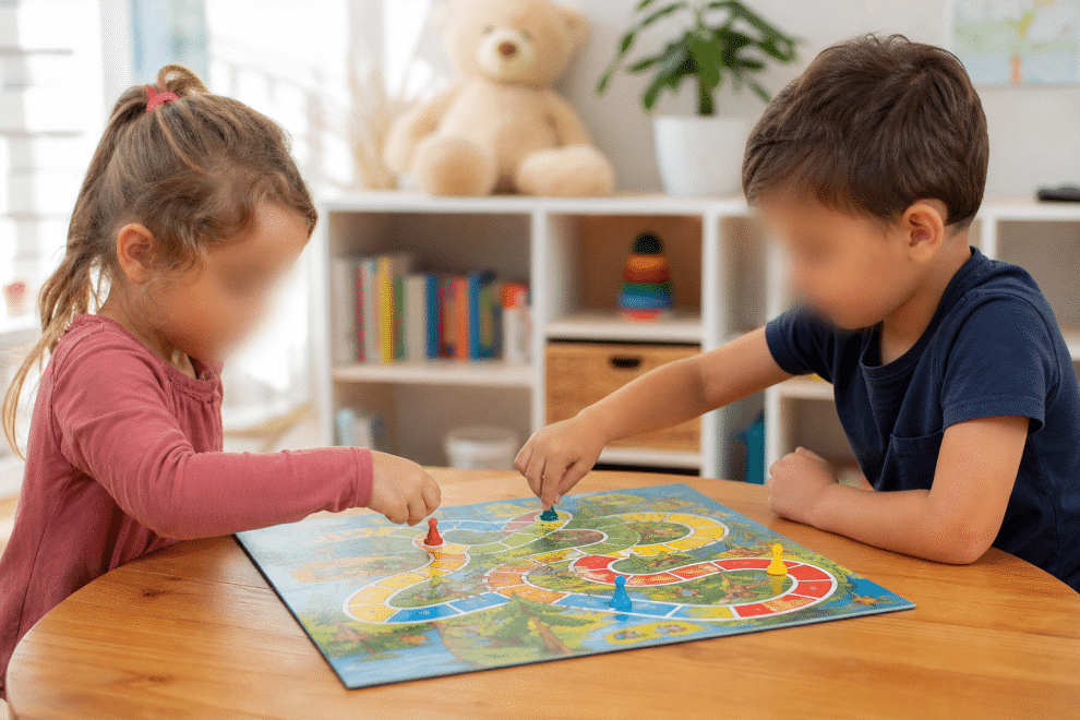 best preschool games — young children playing colorful board game at a table