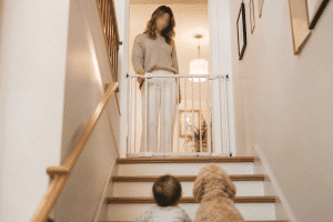 child safety at home — parent beside baby gate at top of staircase