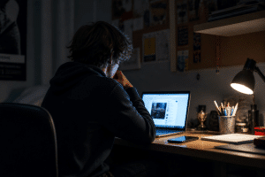 screen time effects on teens teenager using laptop and phone at home desk