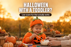 Halloween ideas for toddlers — toddler in a pumpkin costume painting a mini pumpkin among fall leaves