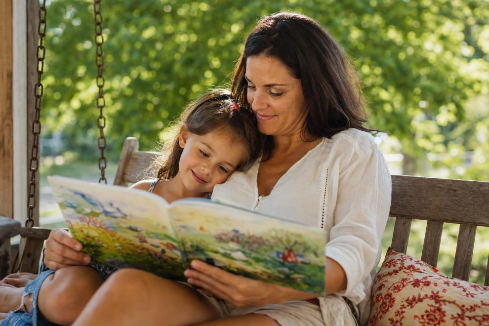How to Prevent Summer Learning Loss: Simple, Joyful Ways to Keep Kids Sharp 15 A mother and young child reading a picture book together on a porch swing on a warm summer afternoon, both relaxed and smiling, illustrating how to prevent summer learning loss through everyday reading