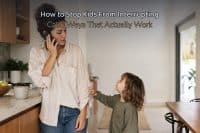 How to stop kids from interrupting — a mom on the phone at the kitchen counter while a young child tugs at her sleeve to talk, with a legible baked-in headline