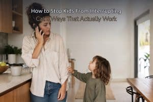 How to stop kids from interrupting — a mom on the phone at the kitchen counter while a young child tugs at her sleeve to talk, with a legible baked-in headline