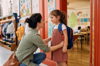 Kindergarten First Day Tips: What to Expect (And How to Make Drop-Off Easier) 1 Parent and child at kindergarten classroom door on first day of school