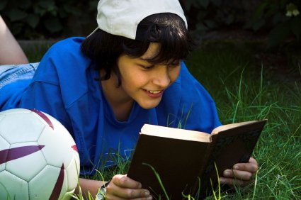 Summer Reading Recommendations for Kids 8 boy enjoying a book outside on the grass