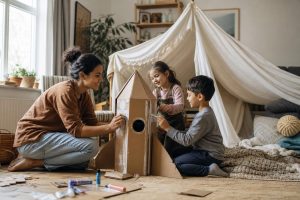 The importance of play in action — children building a blanket fort in a bright family room while a parent sits nearby.