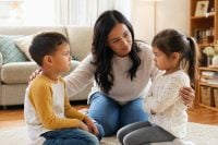 How to Handle Sibling Rivalry Without Taking Sides 1 A calm parent helping two young siblings work through sibling rivalry together