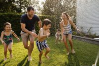 Summer Activities for Kids: Simple, Joyful Ideas for Every Family 1 Summer activities for kids — a family with children playing together in a backyard with a sprinkler on a sunny afternoon, everyone laughing and wet.