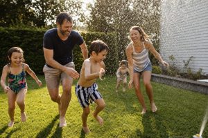 Summer Activities for Kids: Simple, Joyful Ideas for Every Family 9 Summer activities for kids — a family with children playing together in a backyard with a sprinkler on a sunny afternoon, everyone laughing and wet.