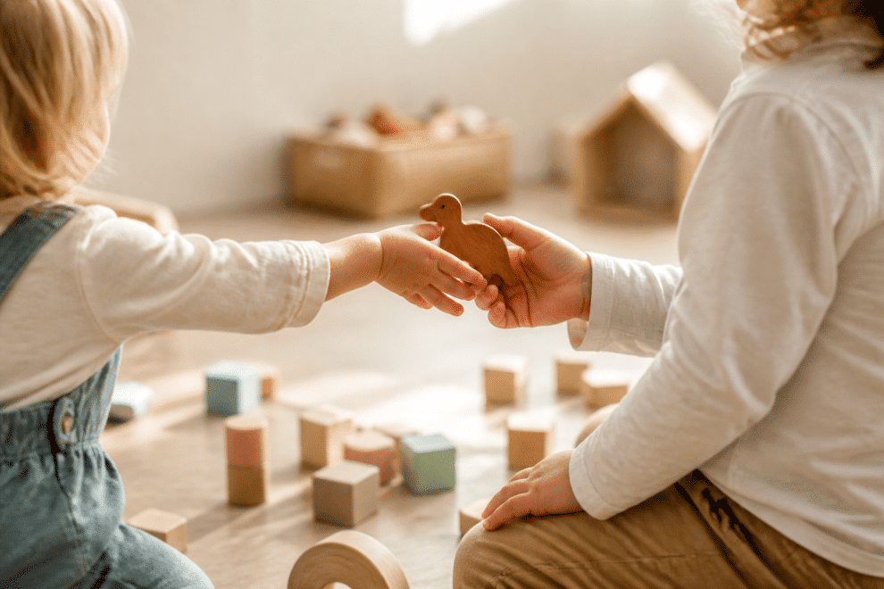 teaching children consideration — child sharing a toy in a sunny playroom
