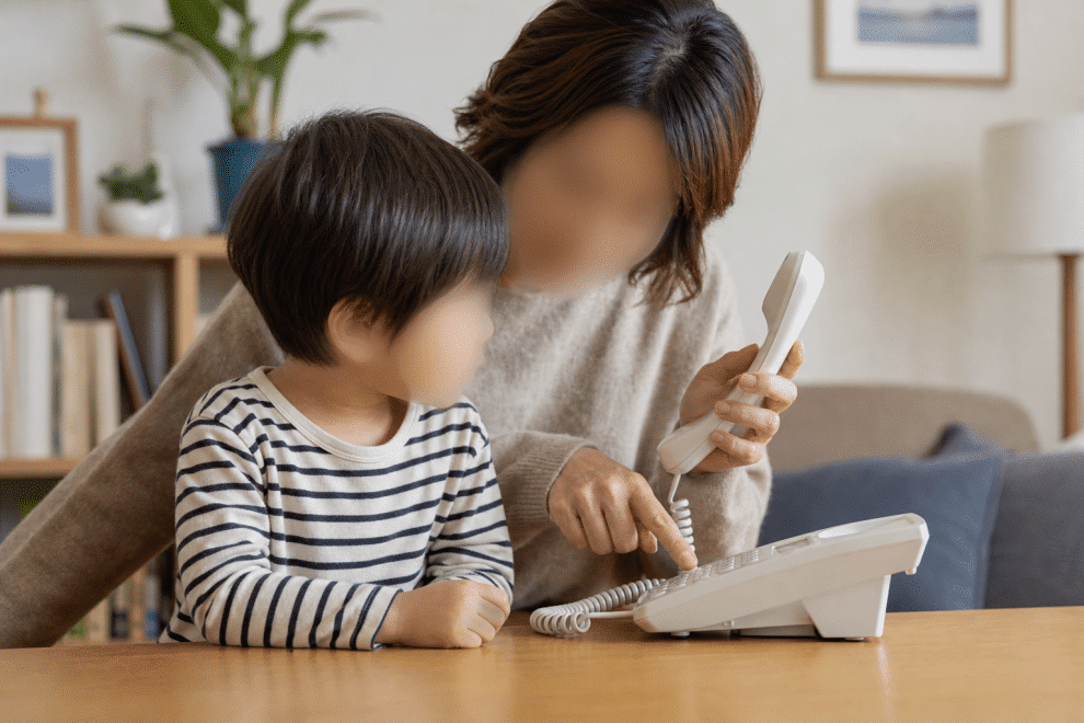teaching kids to call 911 — parent showing child how to use the phone for emergencies