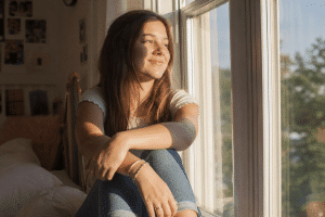 teen self-esteem - confident teenage girl smiling in a bright sunny bedroom