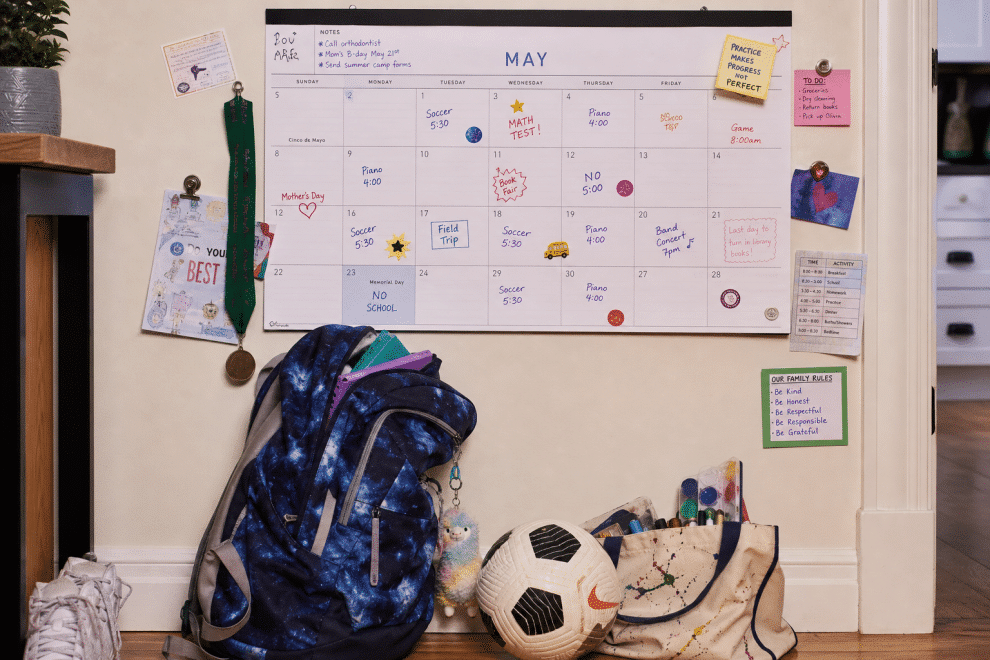 overscheduled kids - packed family calendar with backpack and sports gear piled below